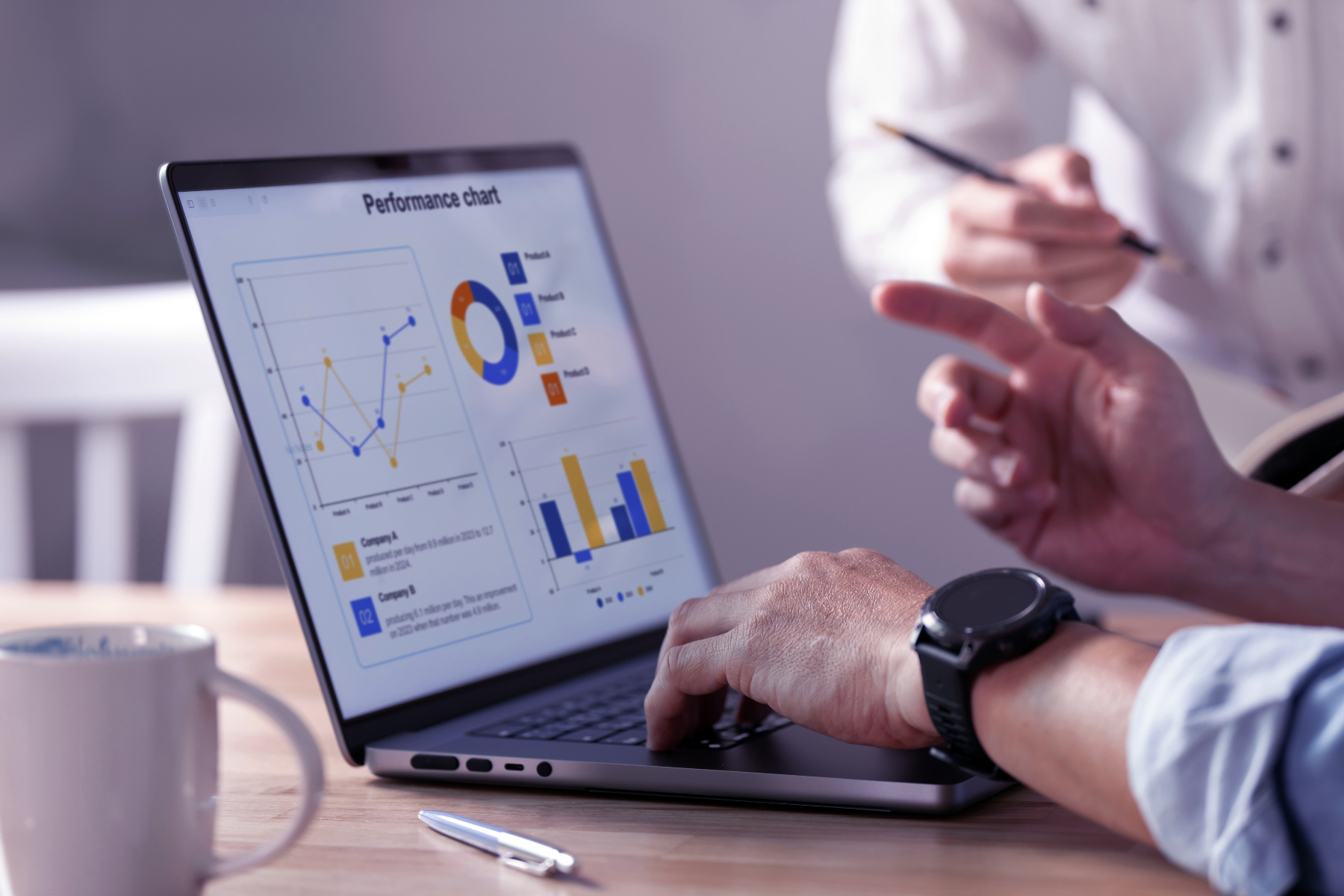 Two people review a laptop displaying a Website Performance chart with graphs and data visualizations. One person points at the screen with a pen, analyzing insights from the SEO Dashboard built for growth.